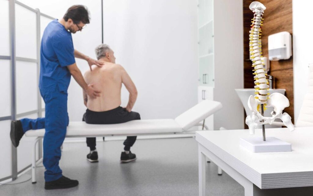 Doctor examining patient with back pain in clinic with spine model